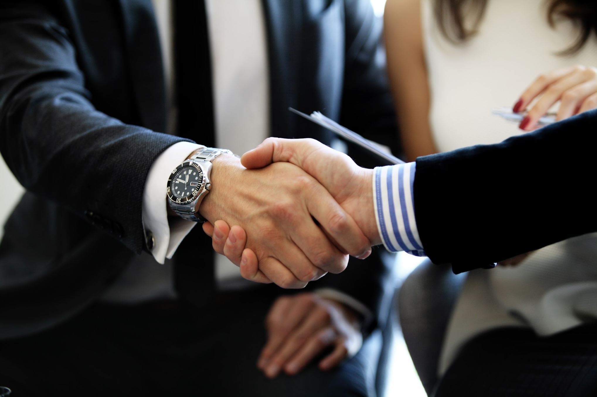 two people in suits shaking hands 