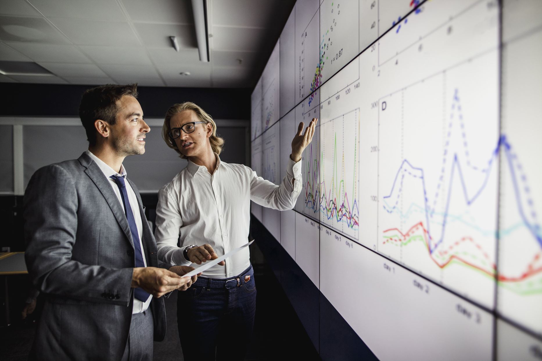 two people looking at graphs on the board and talking