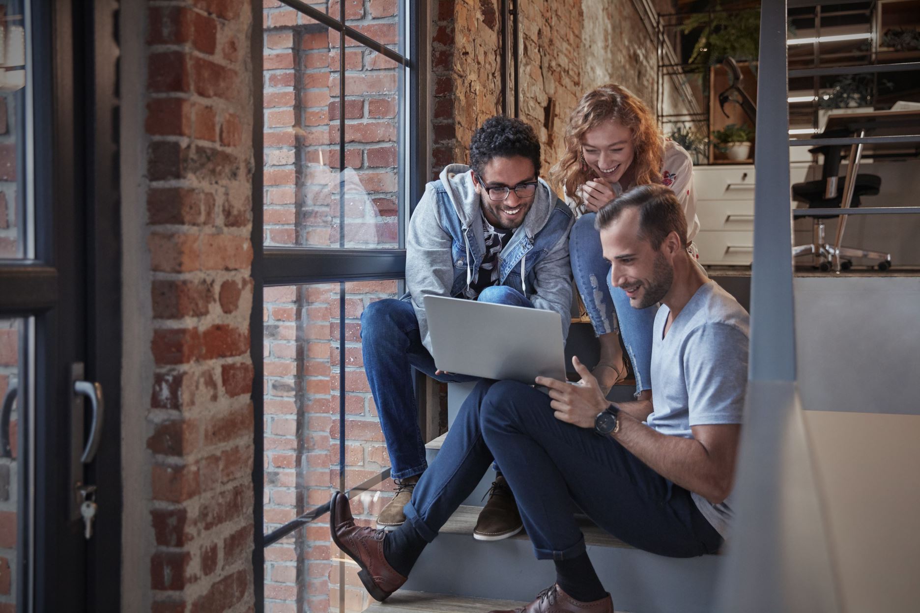 three people on the stairs with a laptop