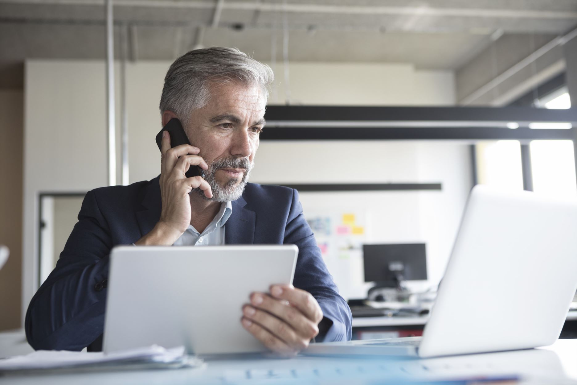 person with papers and a laptop talking on the phone