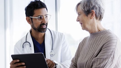 Doctor showing something on the tablet to his patient 